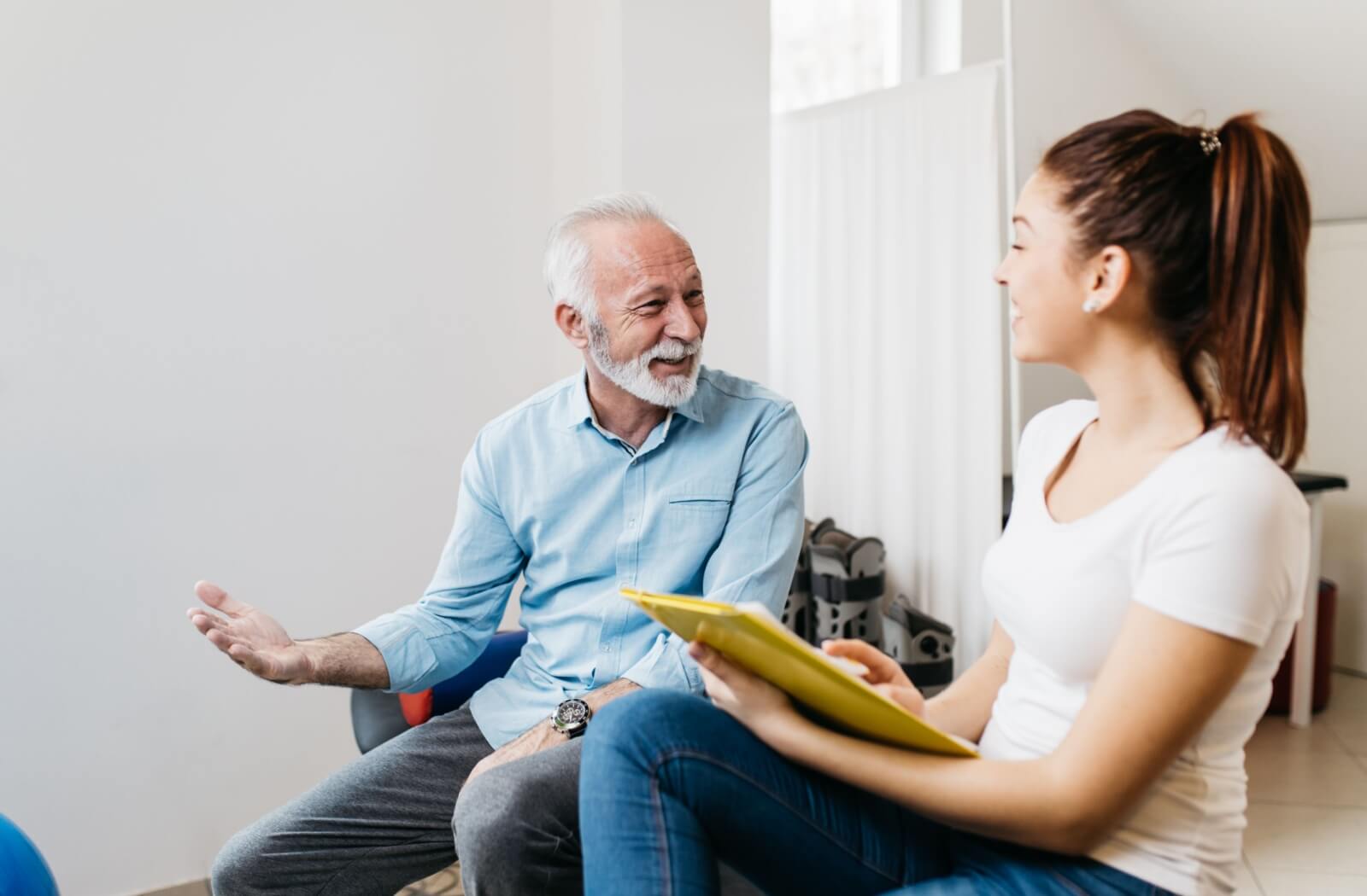 An older adult talking to a physical therapist regarding adaptive products.