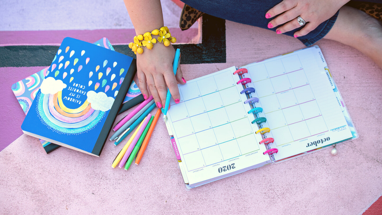A woman with colored markers writing in her daily planners.