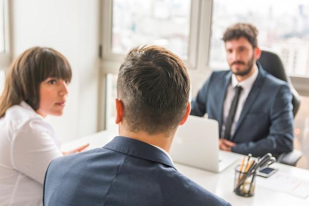 Businessman and businesswoman sitting in front of manager at workplace