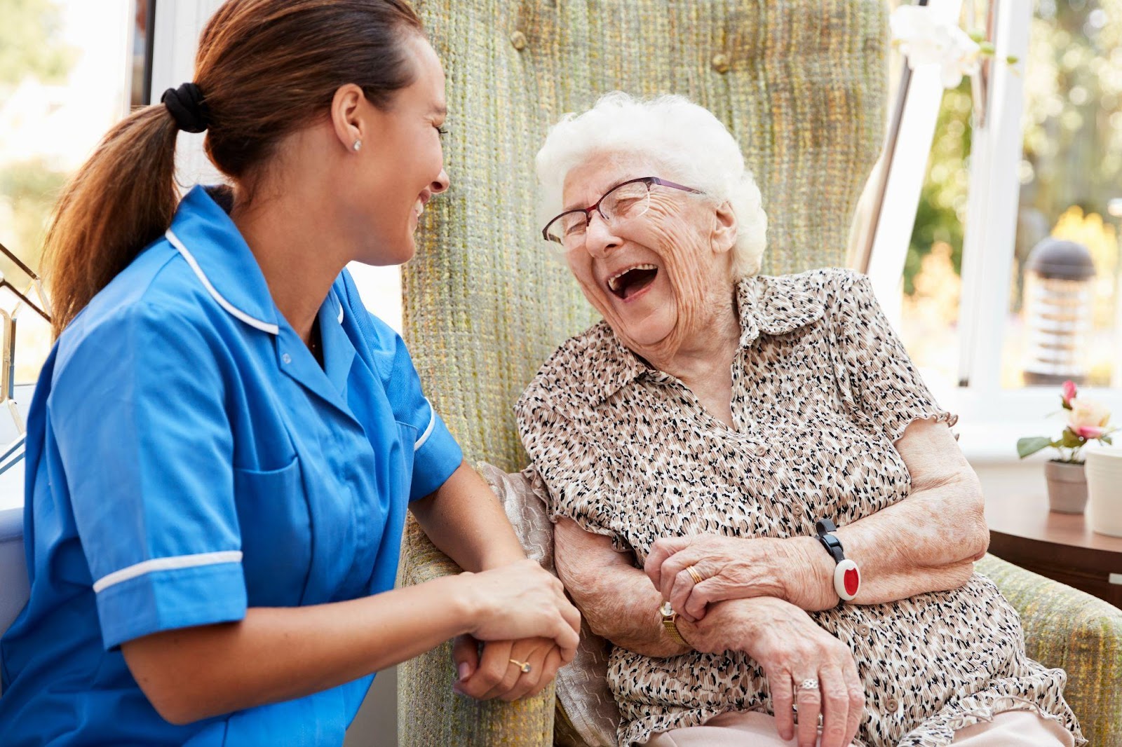 Caregiver and senior woman laughing in an assisted living community