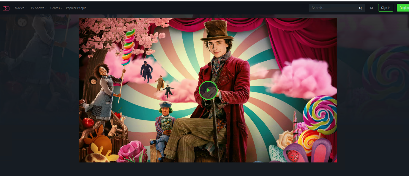 A person in a red coat and top hat sitting on a stage with a curtain and a pink and blue striped backgroundDescription automatically generated
