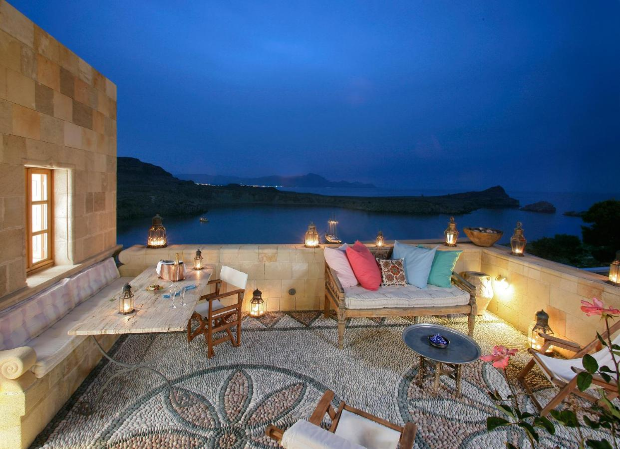 A patio at Melenos Art Boutique in Lindos, with comfortable couches, tables and lights.