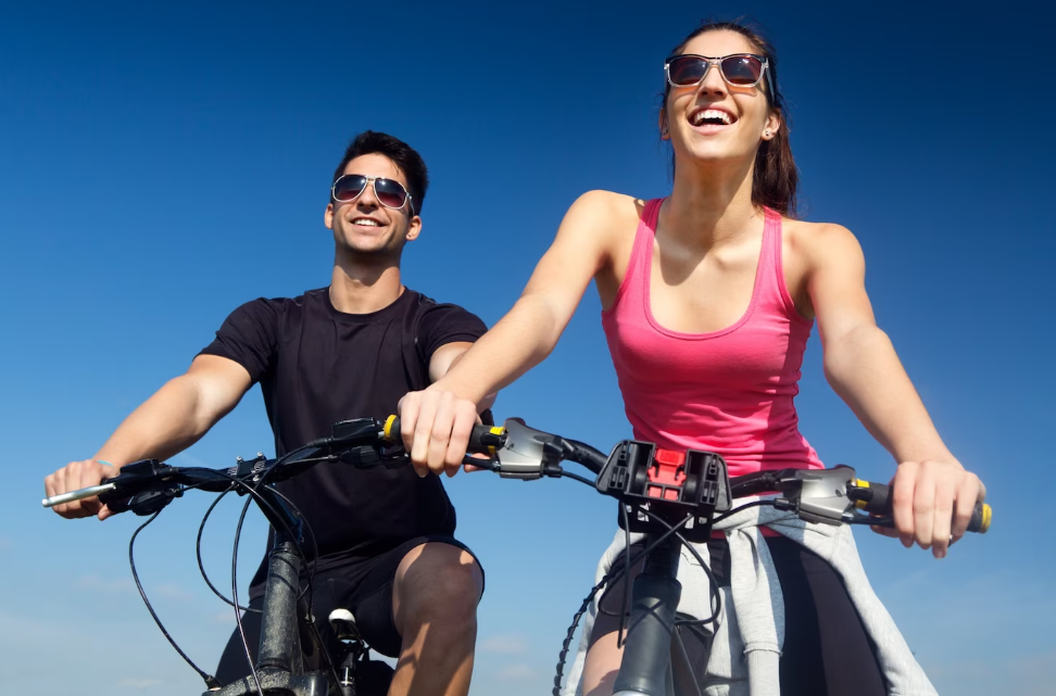 duas pessoas andando de bicicleta no dia azul sorrindo.