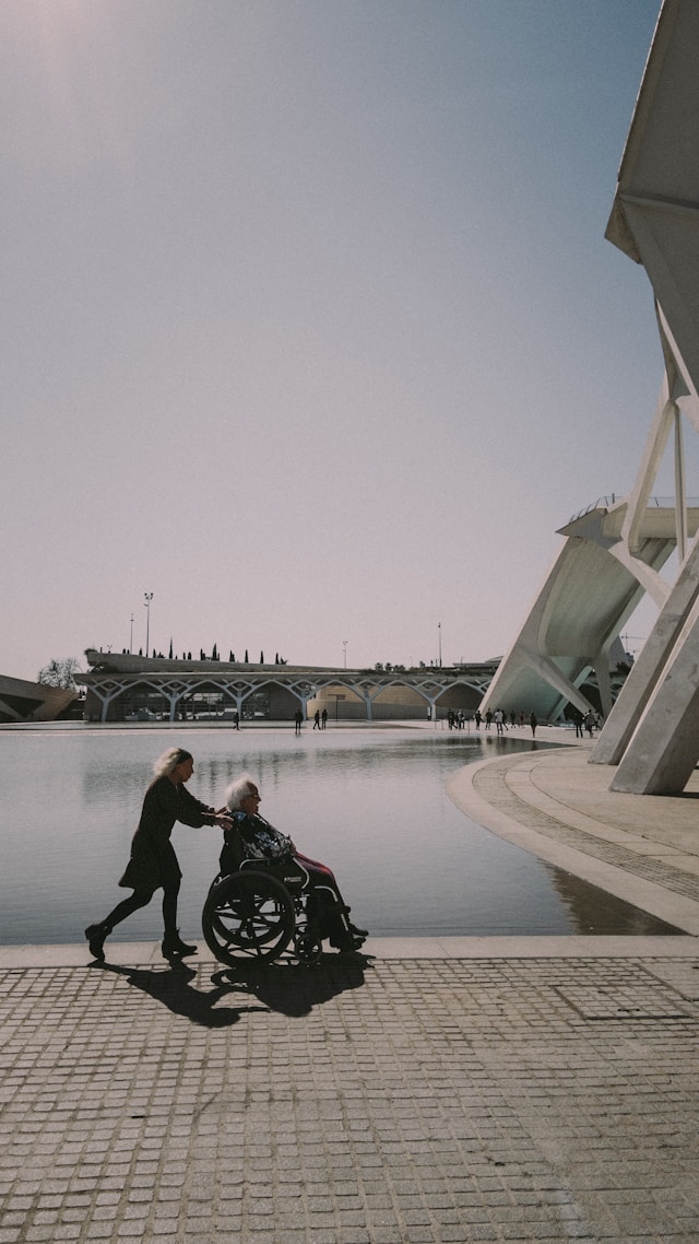 A person moving an elderly person's wheelchair in a public space-The role of human anthropometry in public architecture is very important.