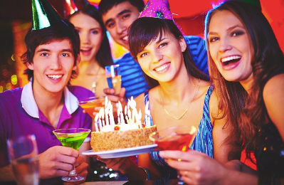 A group of friends joyfully celebrating a birthday party, posing together with a birthday cake.