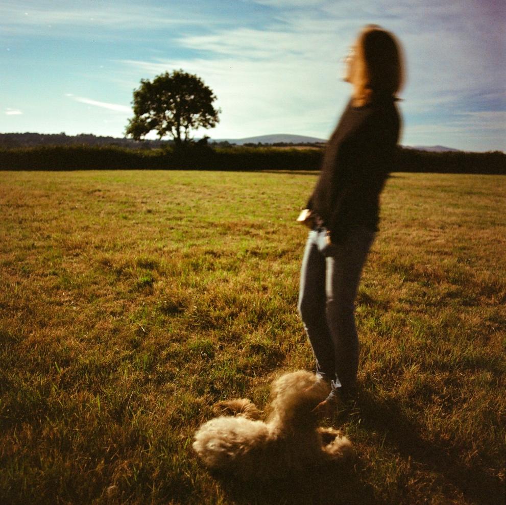 A person standing in a field with a dog

Description automatically generated
