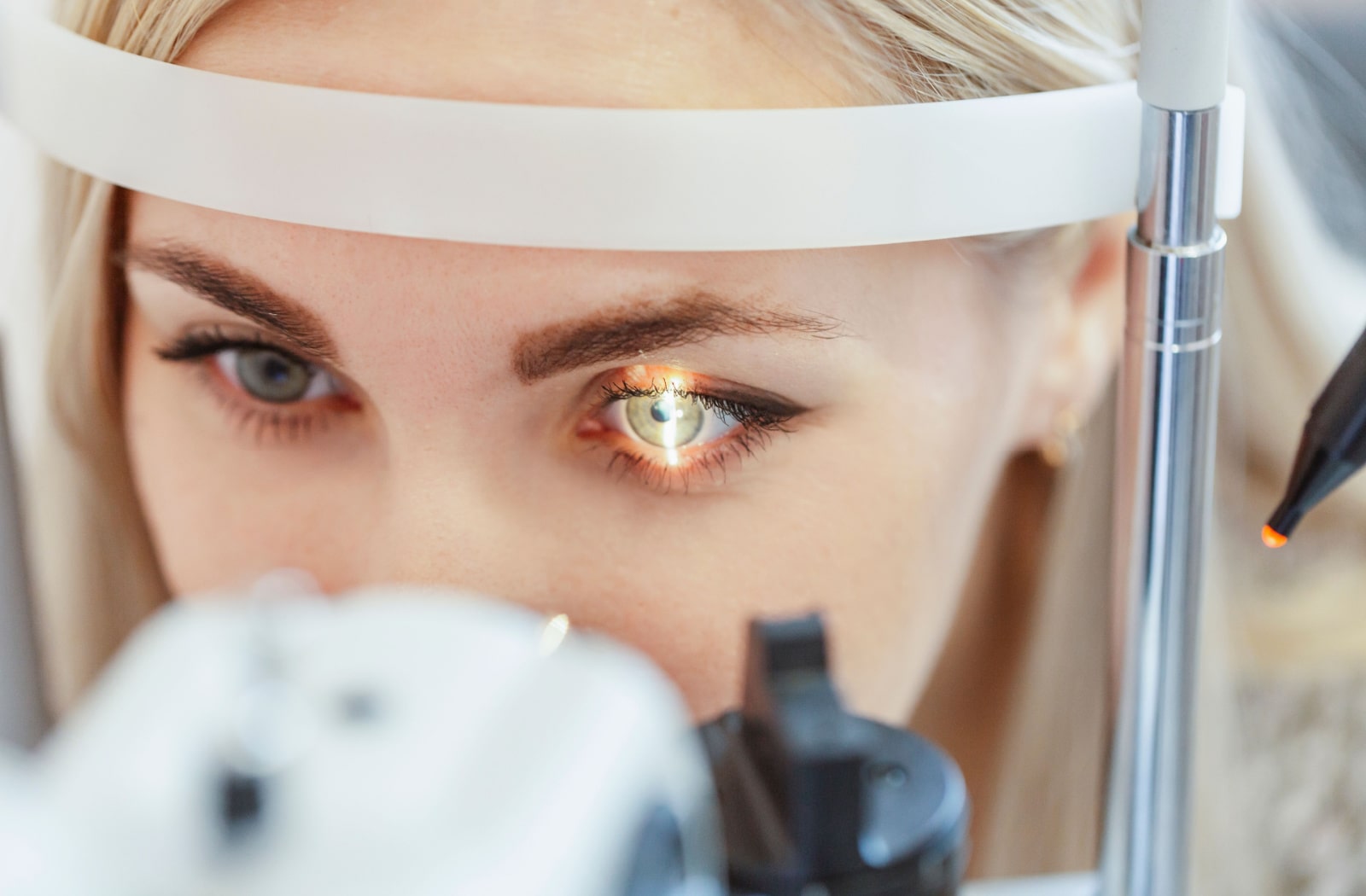 An optometrist uses a slit lamp to examine a female patient's eyes