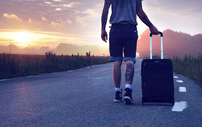 A man with a suitcase on the road because there are many European countries American expats are moving to.