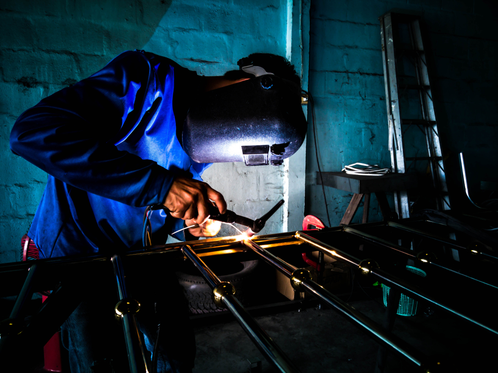 A factory worker welding an iron door