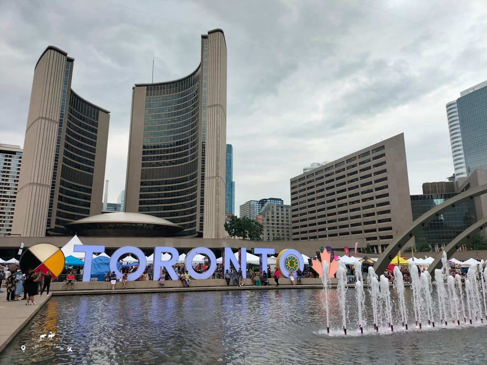 The city's modern city hall and in the foreground the iconic, bright Toronto sign and the fountain in front.