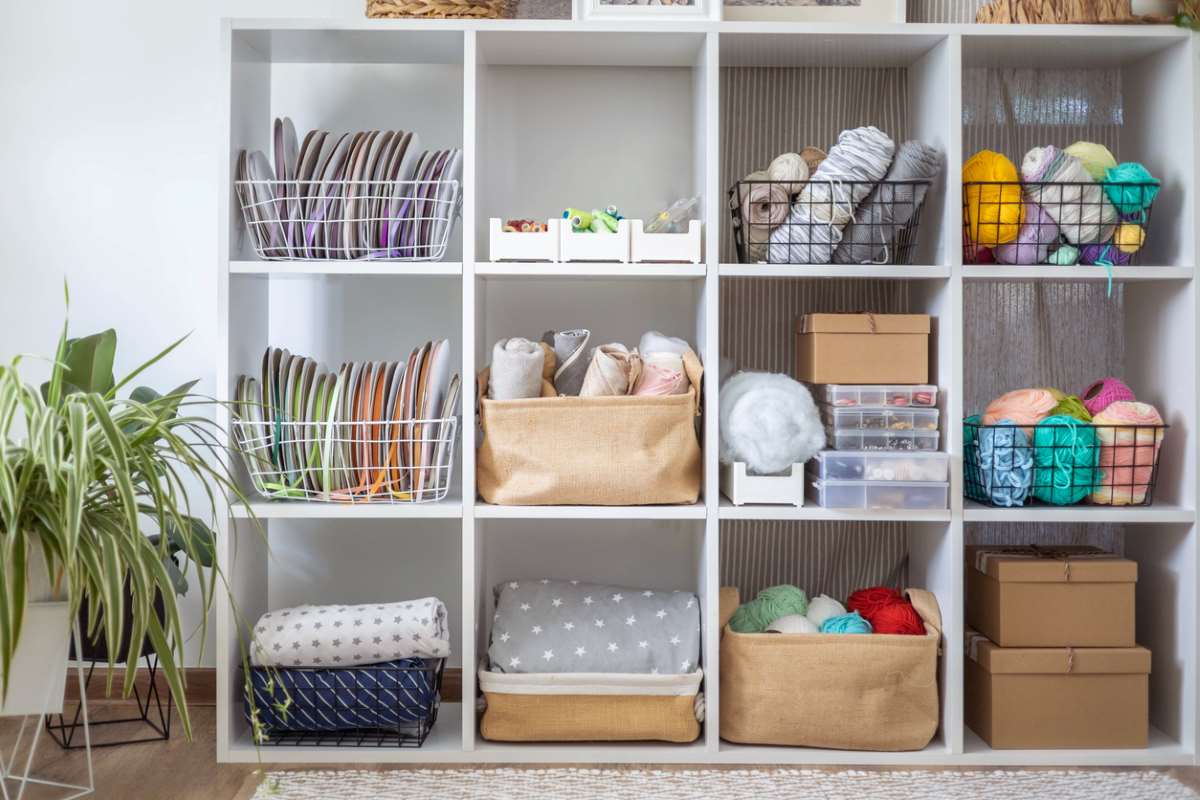 Yarn and textile hobby supplies organized on contemporary cupboard shelves with décor, pictures, and lamps.