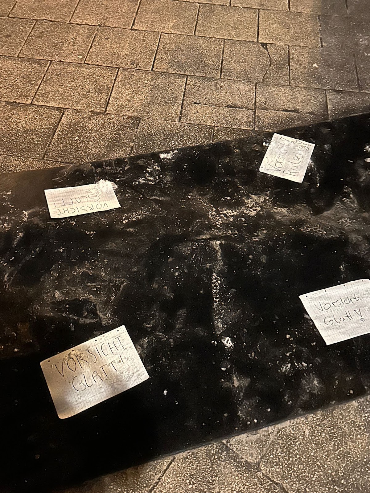 Schilder mit der Aufschrift "Vorsicht Glatt" auf einer rutschigen Matte auf dem Boden in Köln