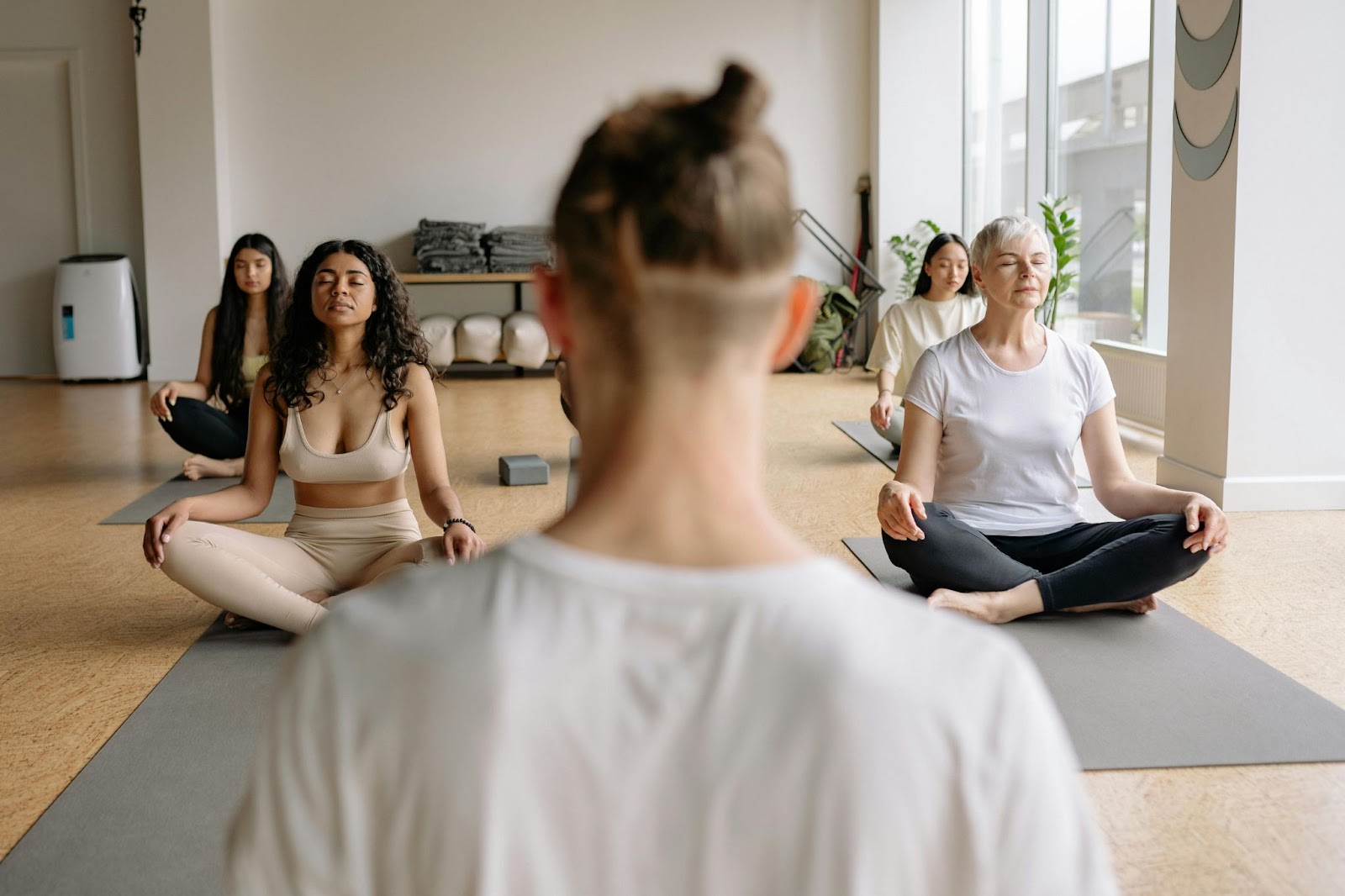 women meditating in a yoga class with an instructor