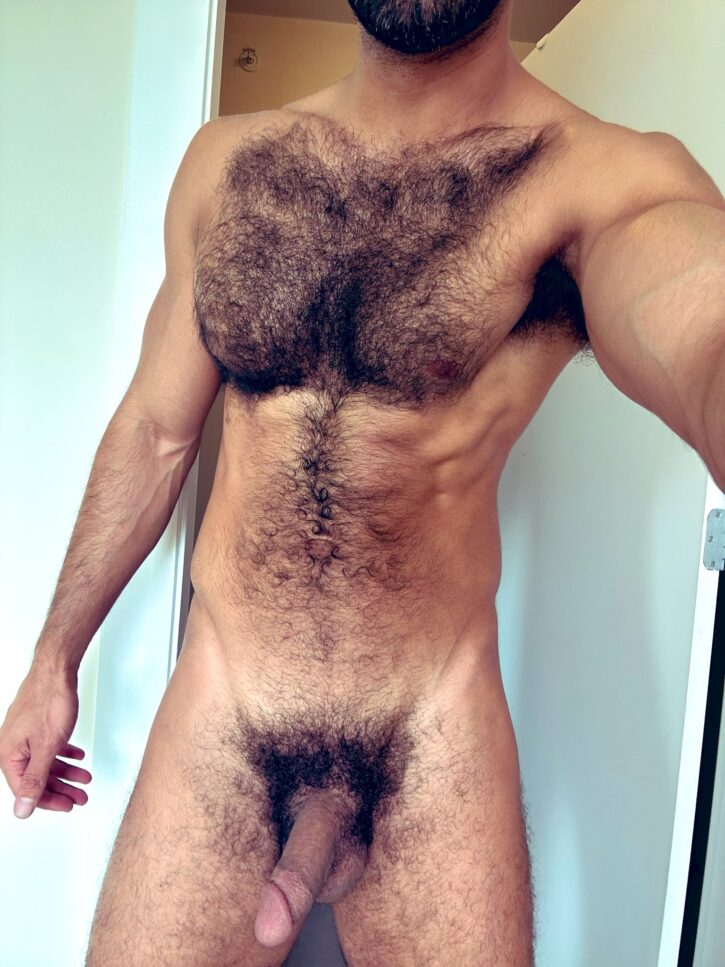 Ali Rush taking a naked selfie showing off his hairy chest and his flaccid cut cock