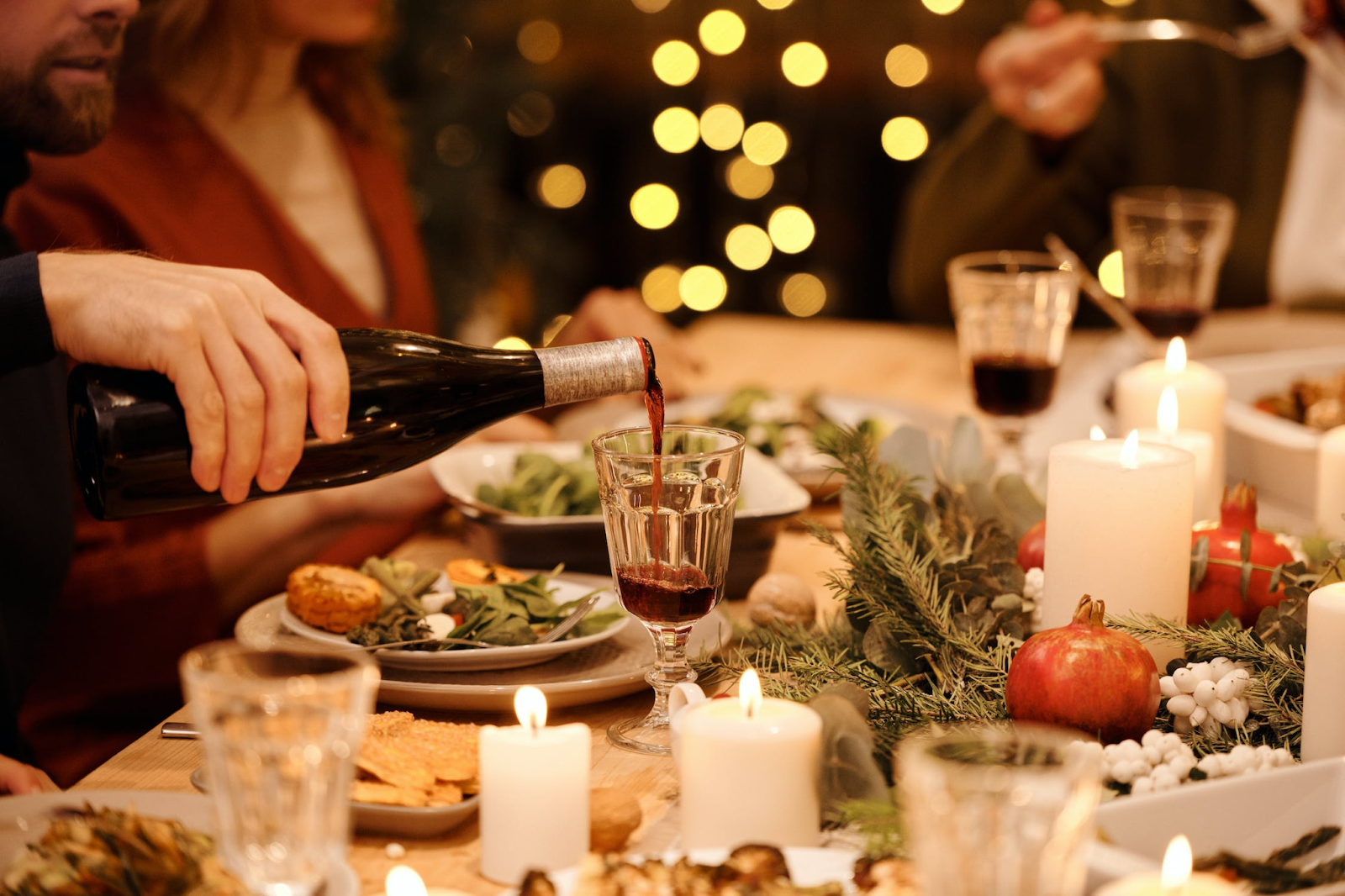 A person pouring wine at a Friendsgiving feast.
