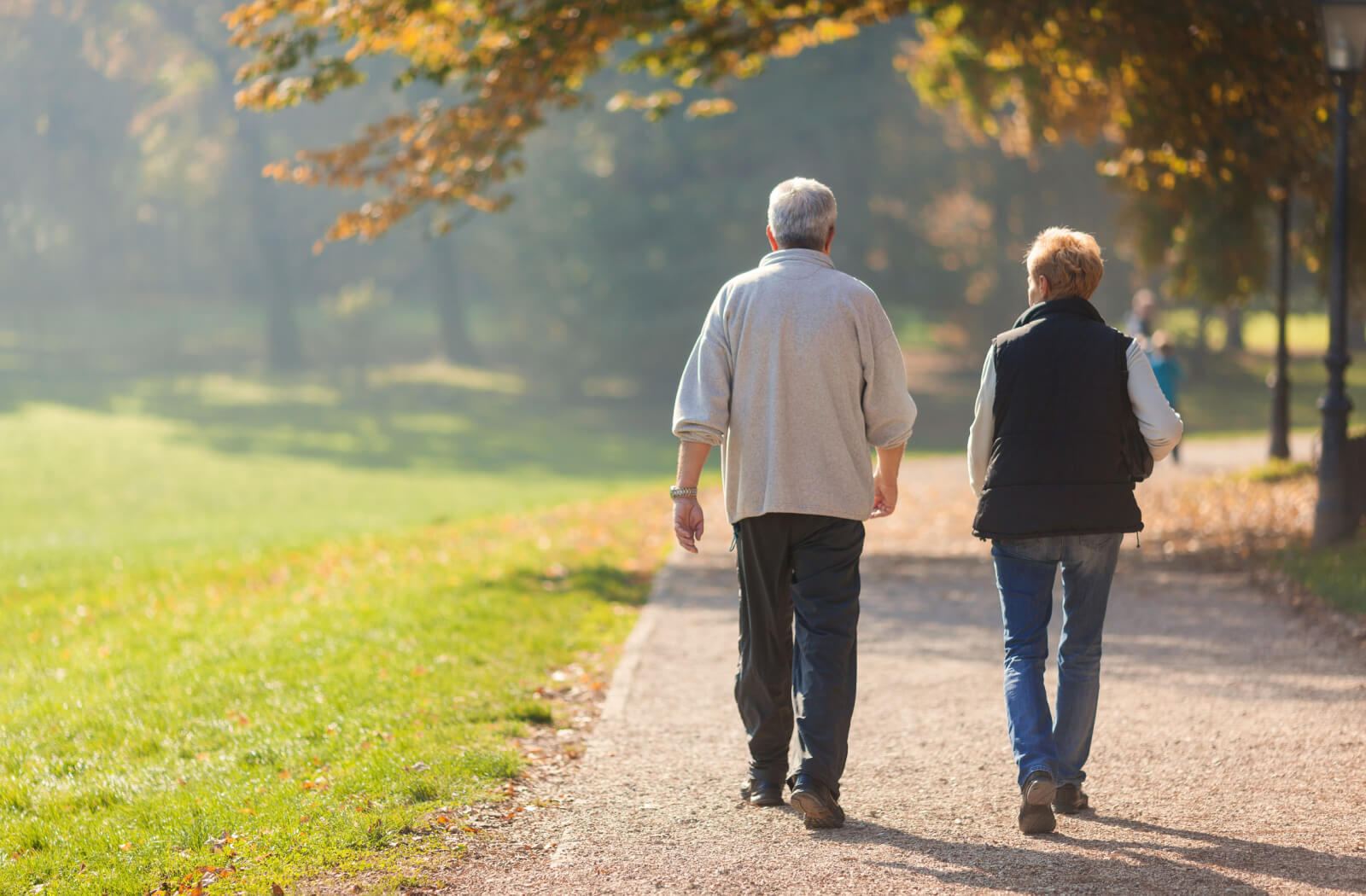 An older adult couple walking at a park.