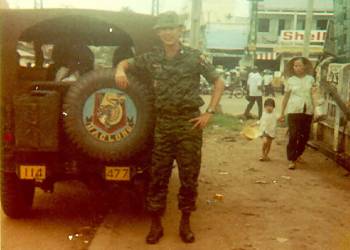 William Griffis poses for a photo in uniform, next to a jeep