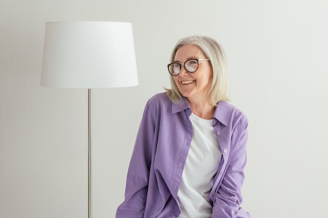 Free A Woman in Purple Long Sleeves Smiling while Wearing Eyeglasses Stock Photo