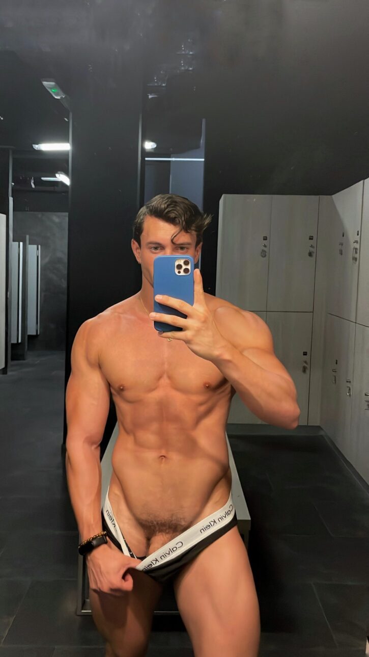 Eric Rmgr taking a shirtless mirror gym selfie pulling down his calvin klein black briefs to reveal the shaft of his gay flaccid cock
