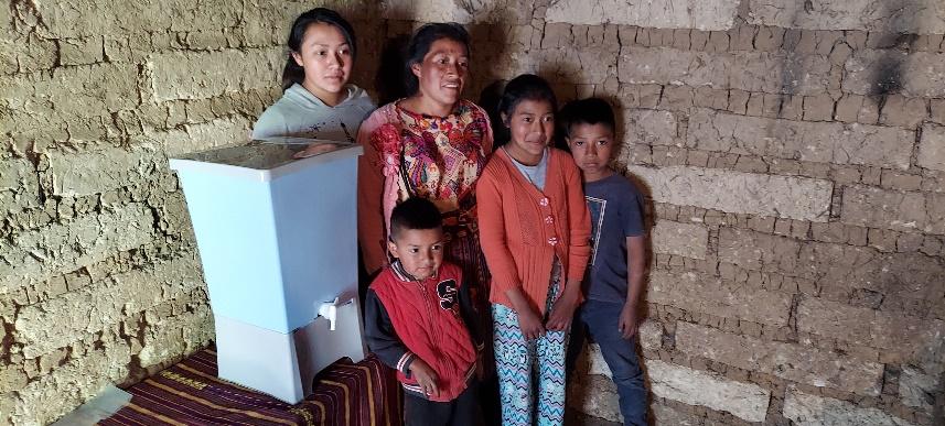 A group of people standing in front of a water coolerDescription automatically generated