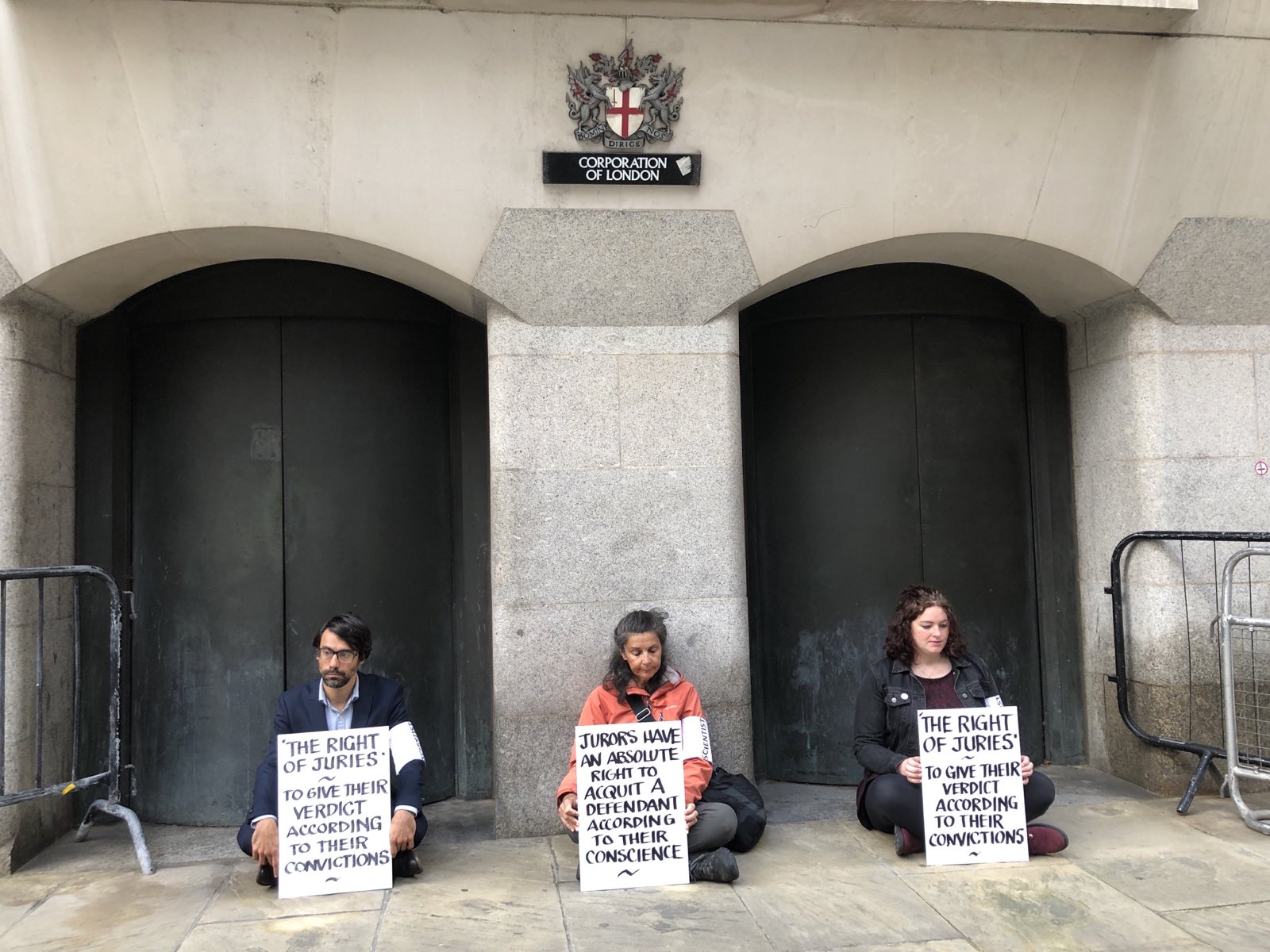 Activists sit with placards outside the Old Bailey in London.