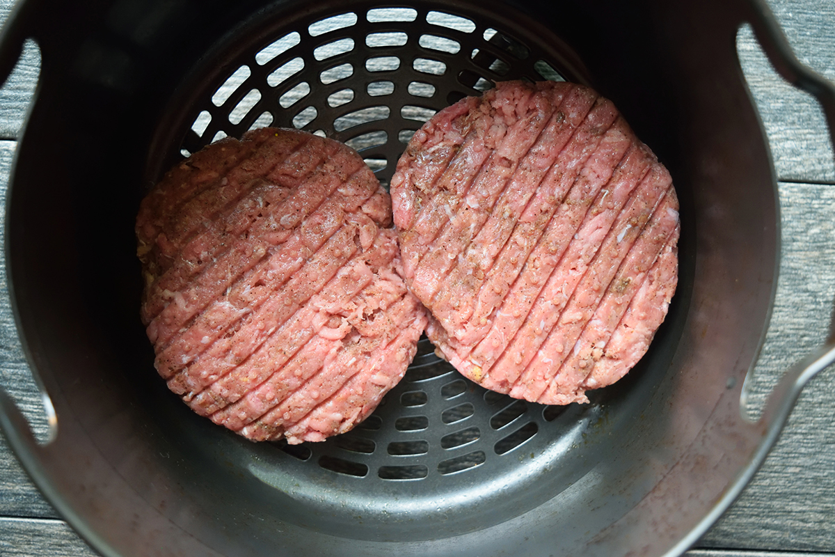 Two turkey burgers in an air fryer.