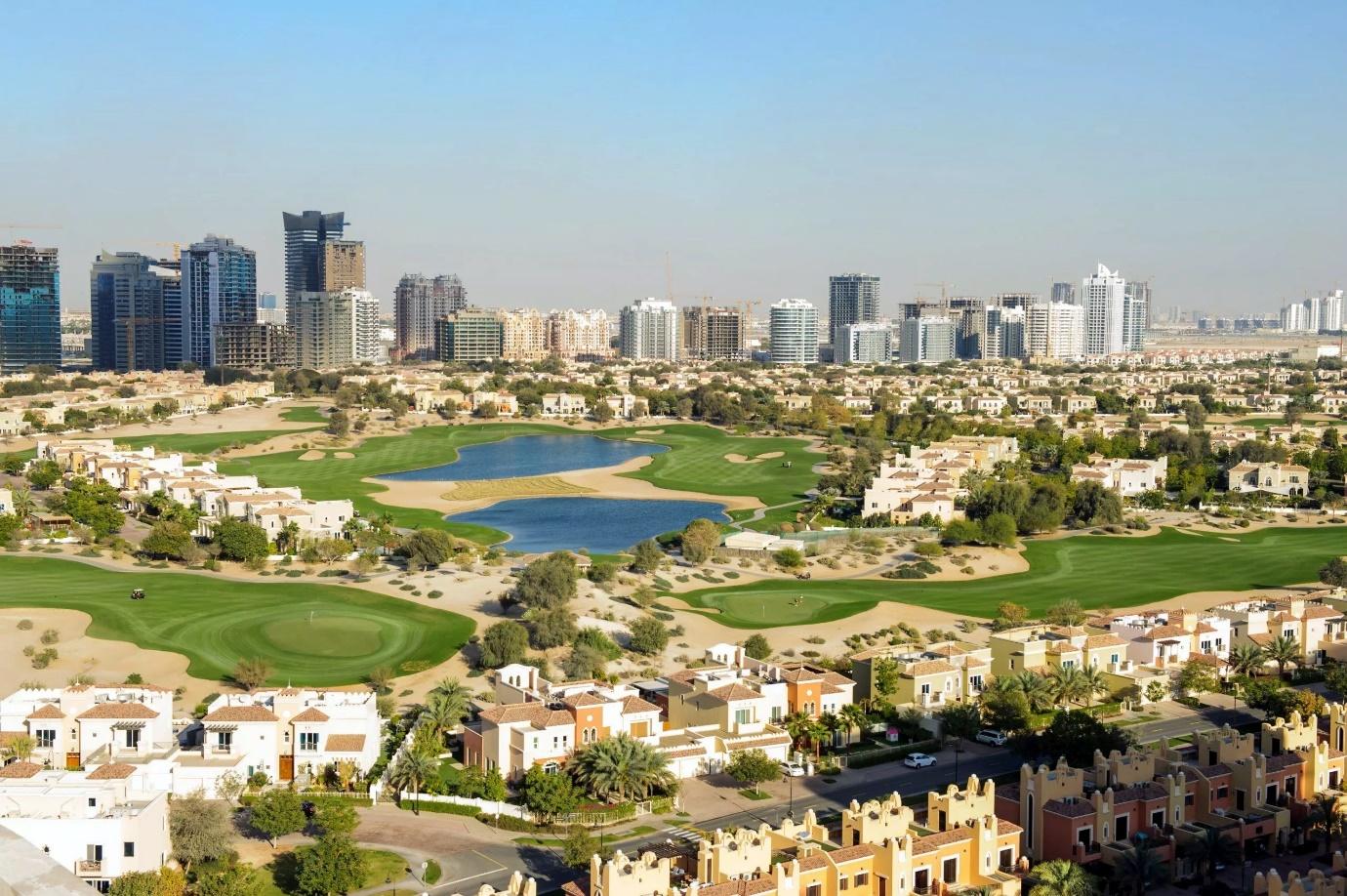 A golf course with a city in the background

Description automatically generated