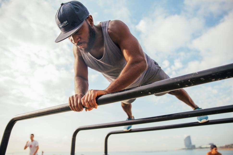 Man doing diamond pushups on a gymnastics bar