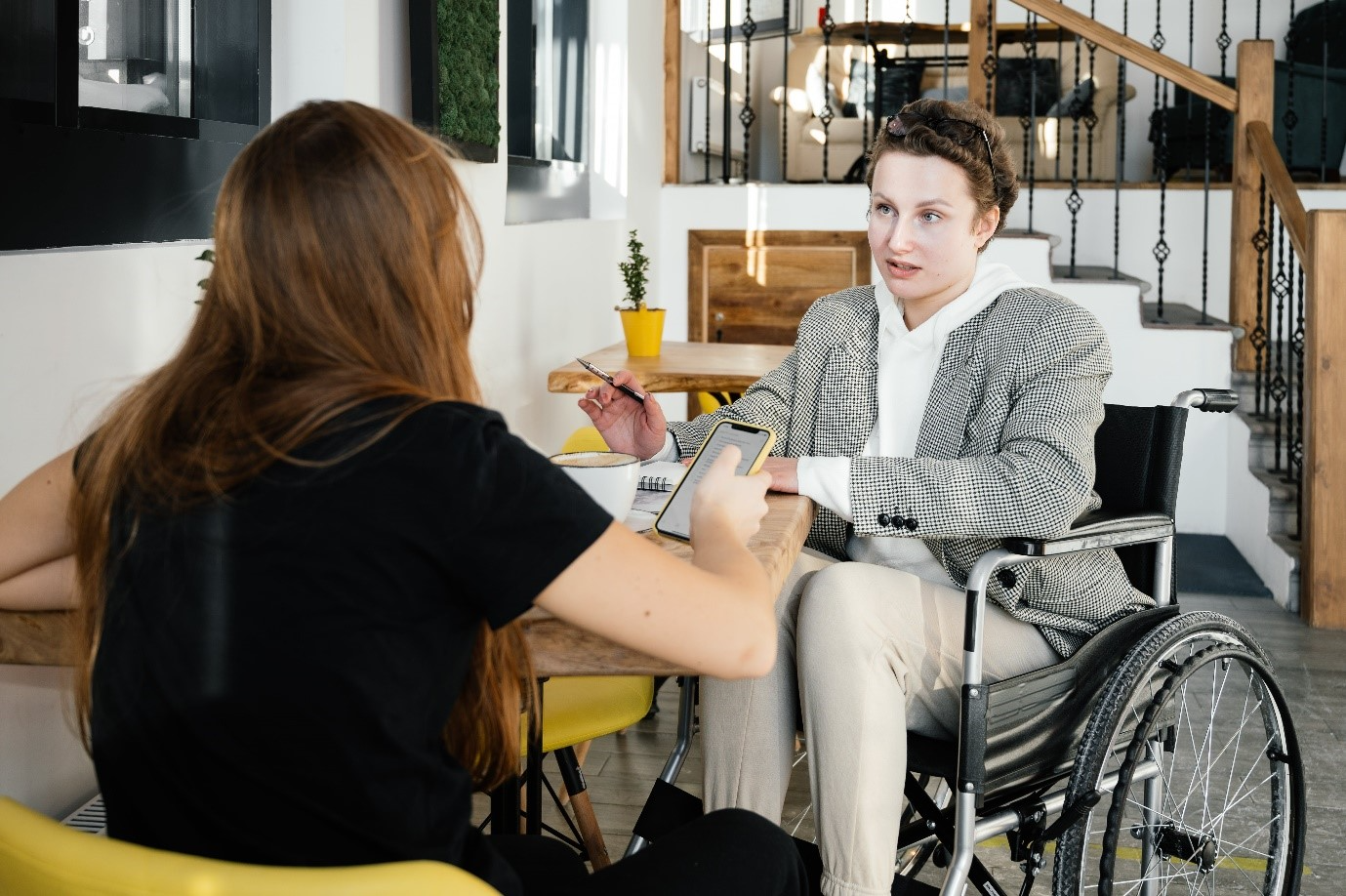 A person sitting at a table with a person in a wheelchair (Accessibility and Inclusion blog)