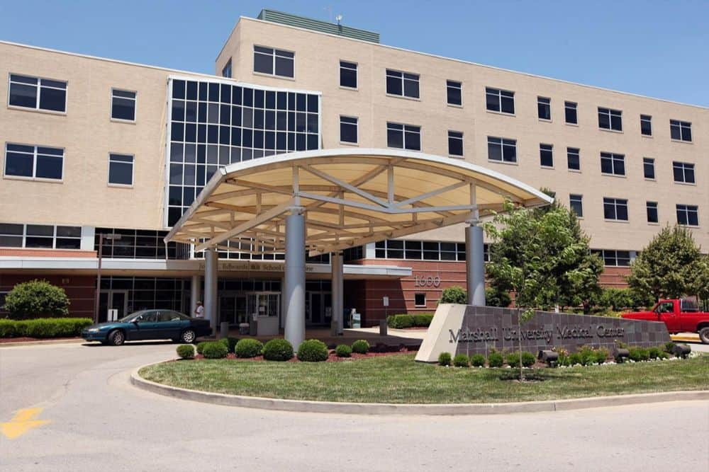 Exterior of Marshall University Joan C. Edwards School of Medicine building with trees and blue sky in the background.