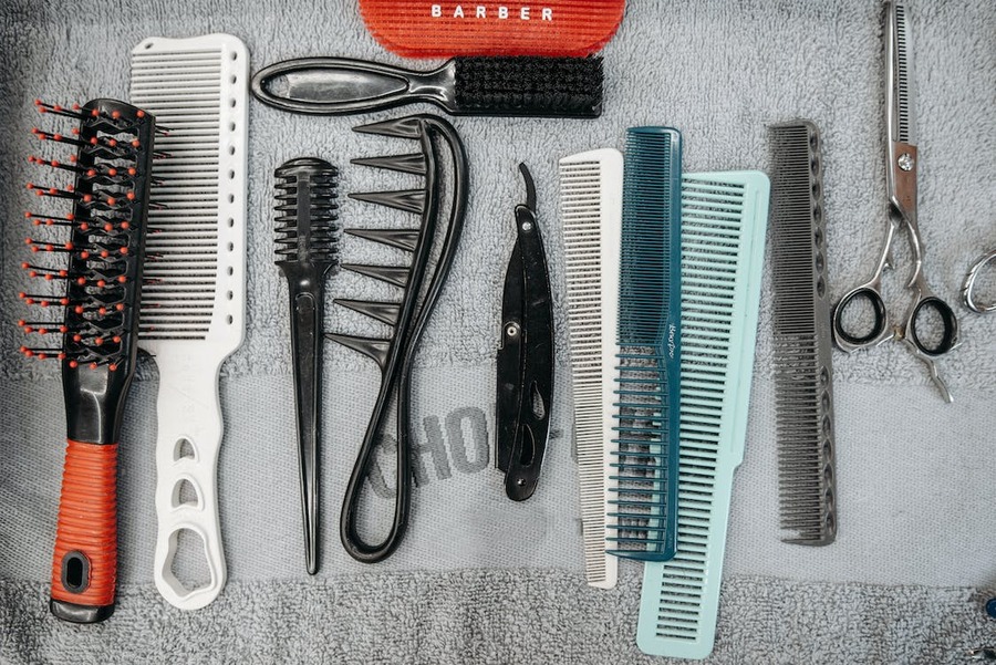 Plastic combs and scissors on a grey towel
