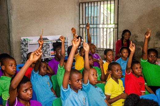A group of children raising their hands

Description automatically generated