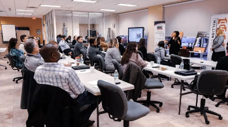 A group of people sitting at tables in a room; Entrepreneur Collaborative Center