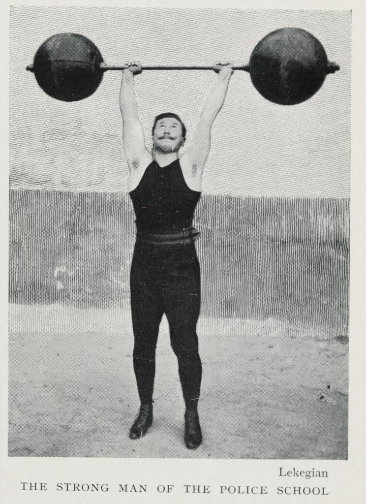 Black and white picture of man holding one of the original barbells