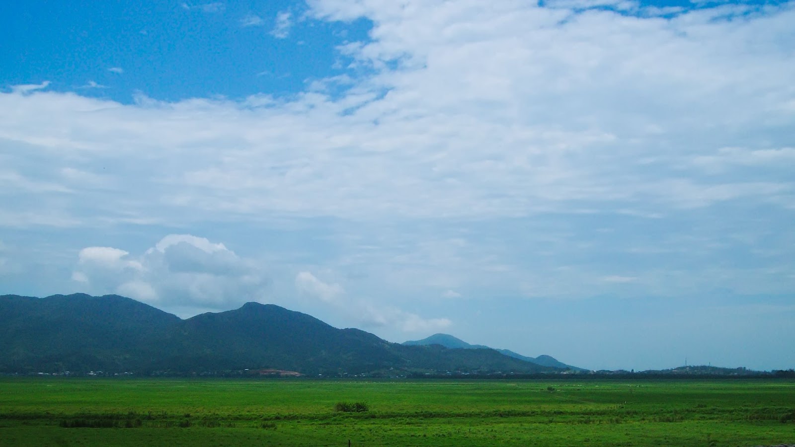 Extensa planície com gramado verde no Parque Nacional Guaricana. Ao fundo, aparecem desfiladeiros de montanhas