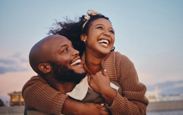 Premium Photo | Happy black couple love and hug laughing in joyful happiness  for bonding time together in the outdoors african american man and woman  enjoying playful fun piggyback with smile for