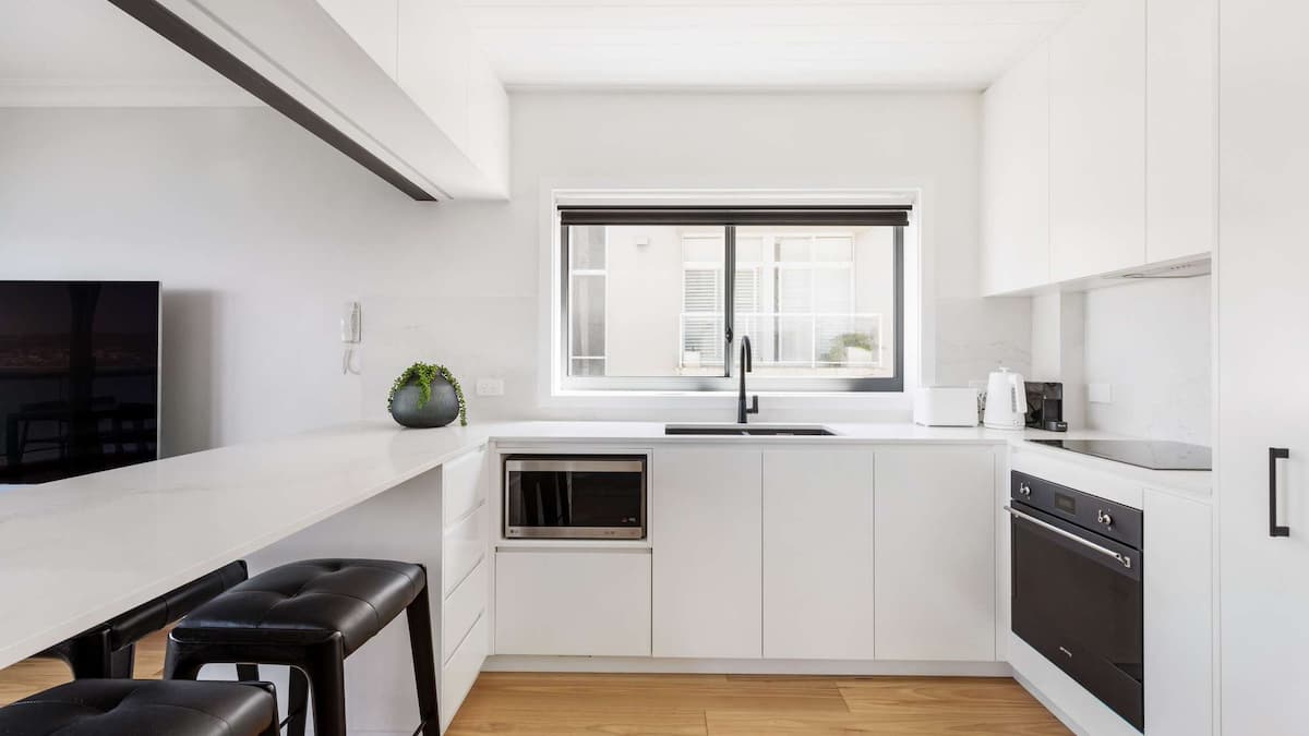 Clean white kitchen with microwave, oven and stove 