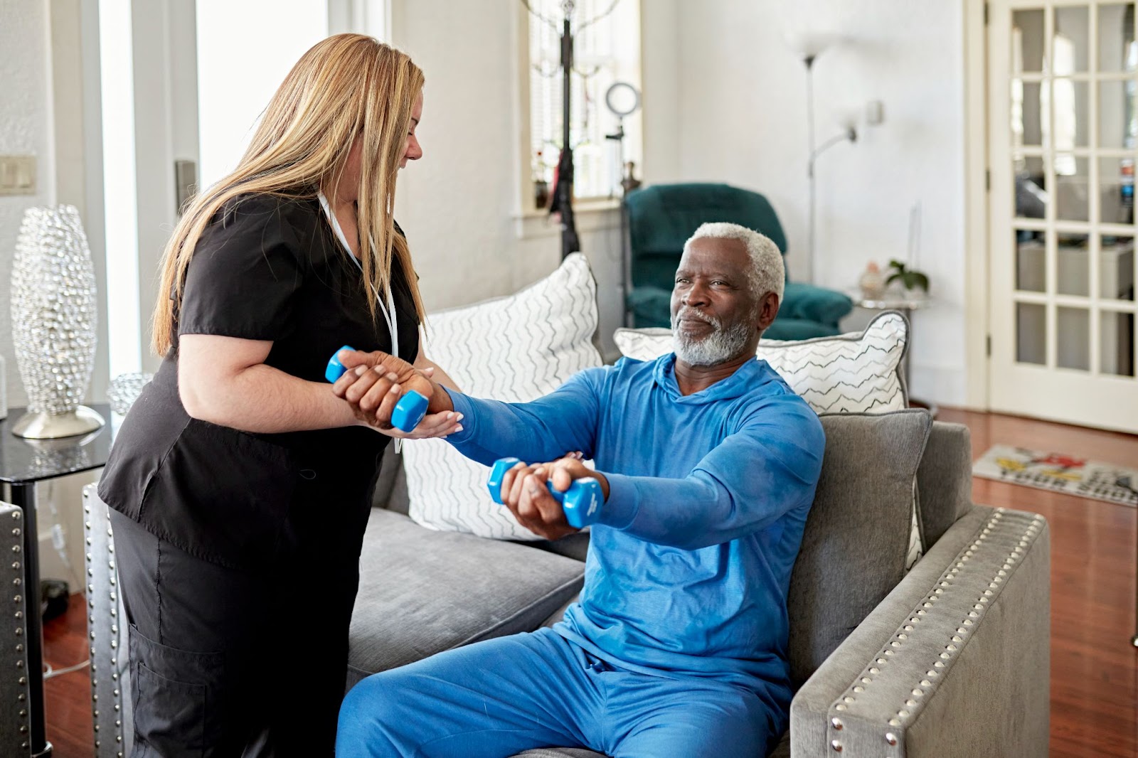 caregiver doing weighted exercises with elderly man