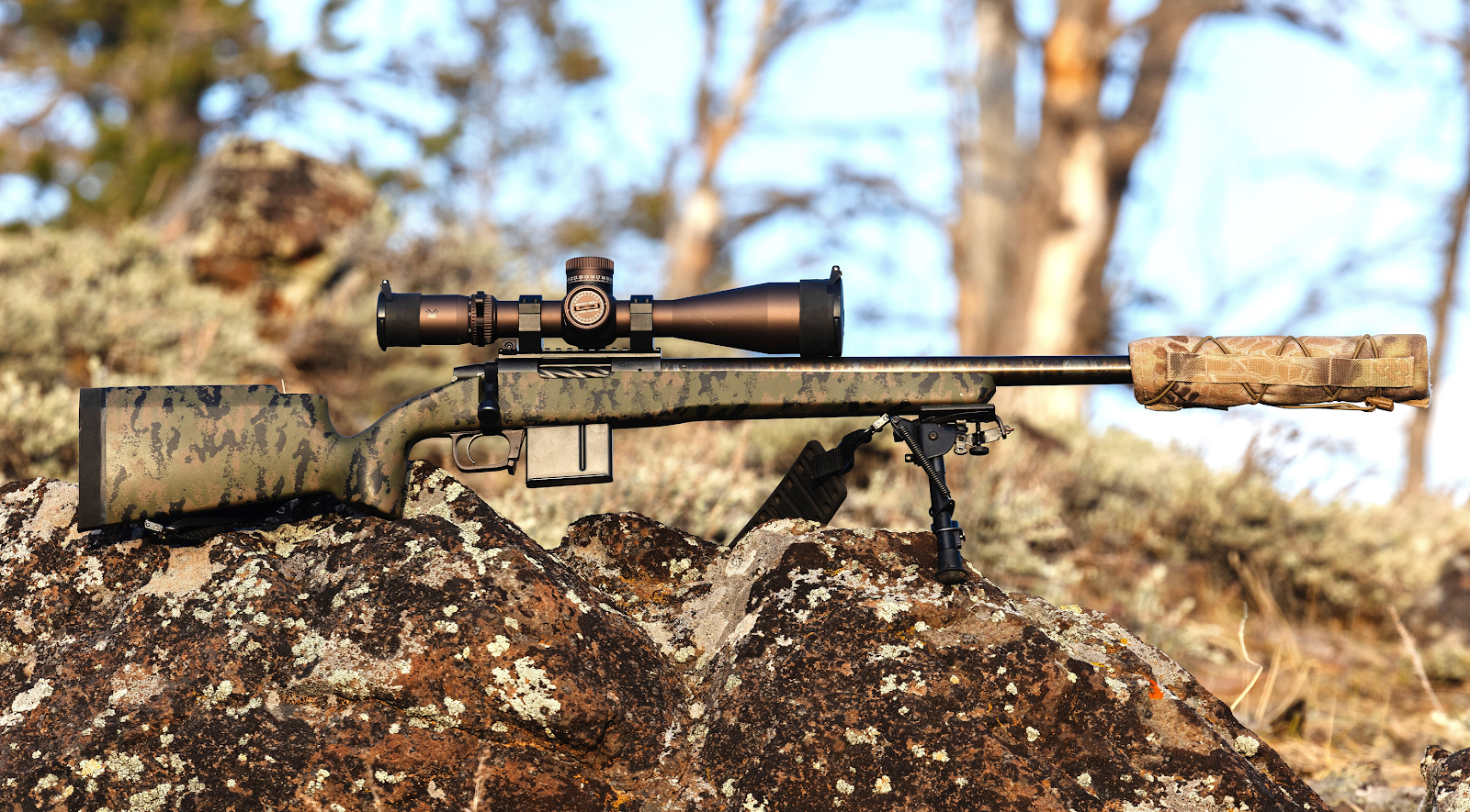 A rifle with a scope on a rock

Description automatically generated
