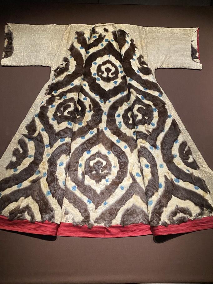 A brown and white robe with blue designs

Description automatically generated