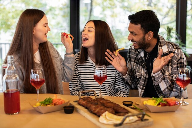 Friends enjoying food and drinking wine at Friendsgiving.