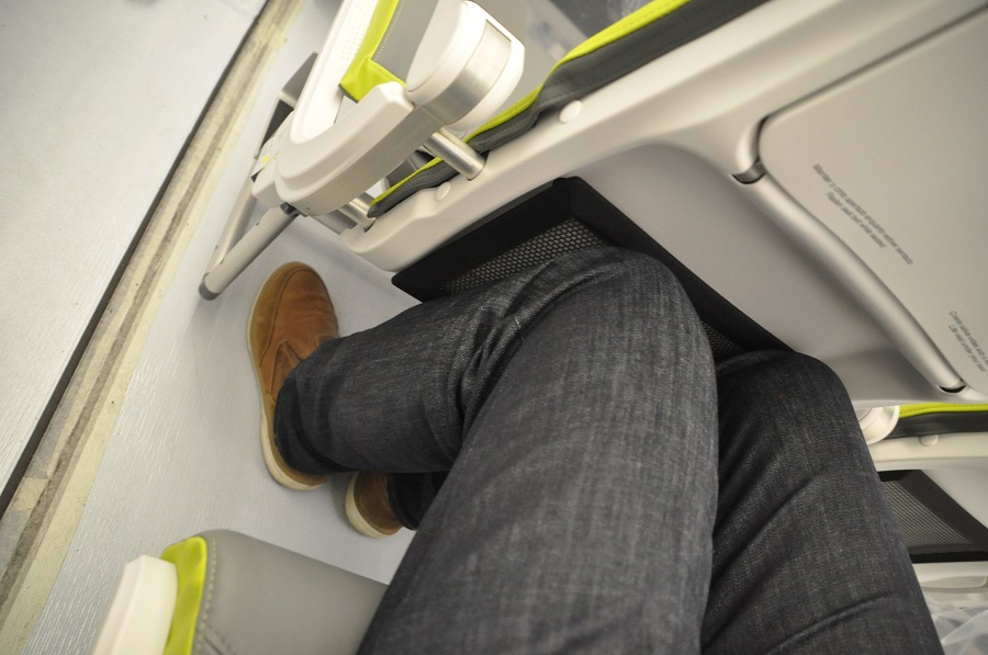 An economy class seat of TAP Air Portugal aircraft is shown where a man is sitting and his legs are touching the front seat. he is not comfortable. this shows that how cramped is the seating on a standard aircraft of Portugal's national carrier.