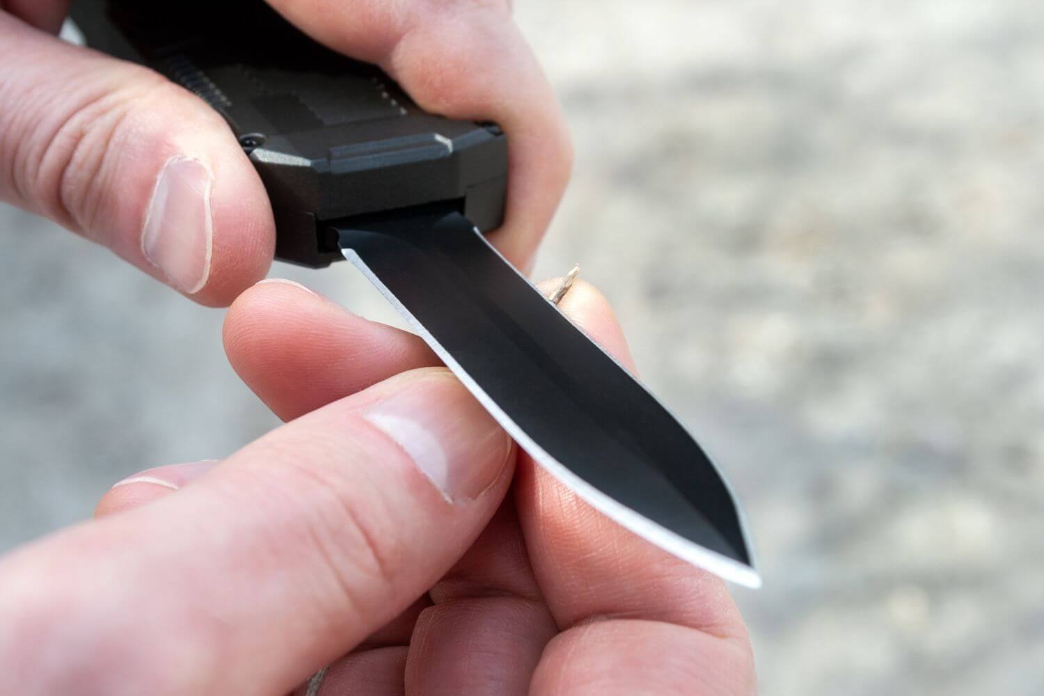 hands holding an everyday carry knife, with fingertips touching the blade of the knife