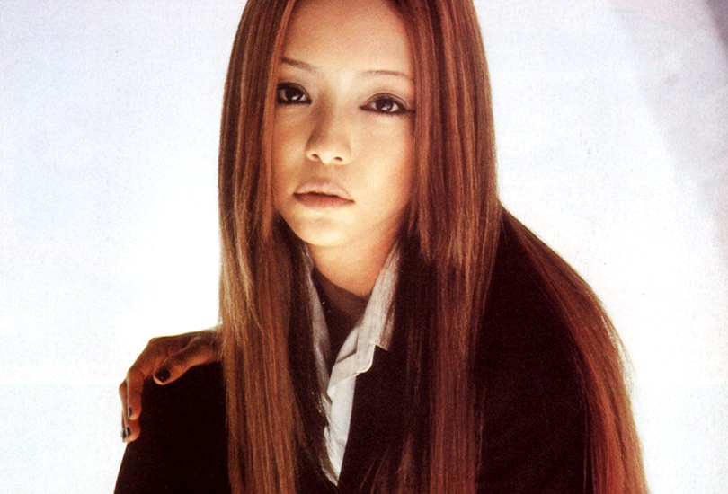 A shot of Namie Amuro from the Genius 2000 album shoot. Namie is crouched down, wearing a black suit with a white shirt and black nail polish. (Image credit: Namie Amuro Toi et Moi V4 @ https://www.amuro.fr/)
