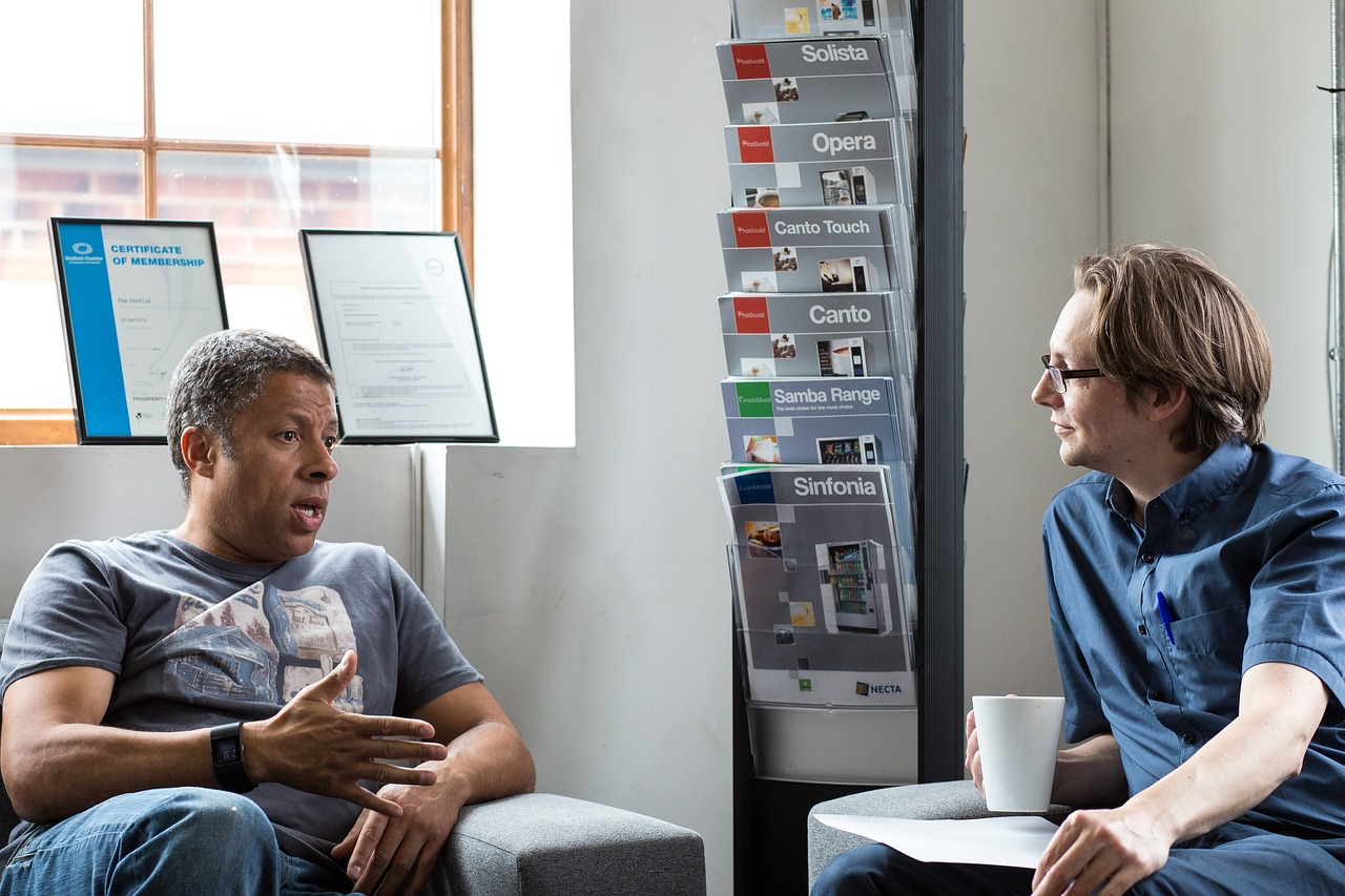 Two male colleagues talking in a relaxed setting.