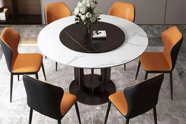 A contemporary dining area with a circular marble table, orange and black chairs, and a grey rug, exhibiting a chic, modern style.