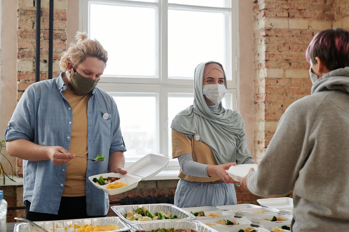 Free Volunteers Giving Out Meals Wearing Face Masks Stock Photo