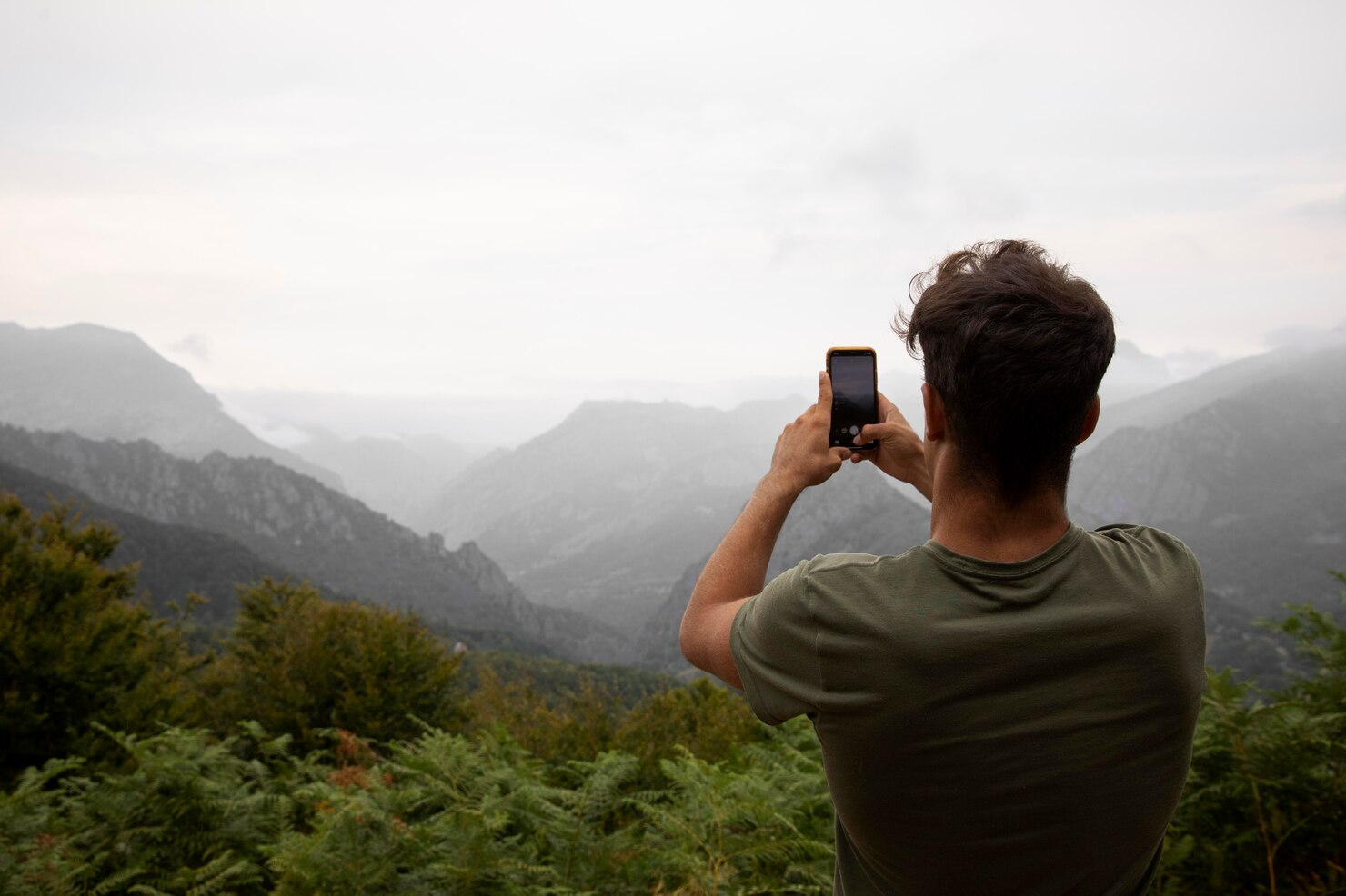 A man taking a photo of the mountains.