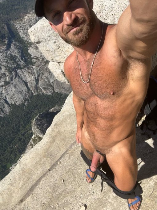 Bruce Jones with his pants down at cliff edge outside taking a nature selfie and smiling with his cock out
