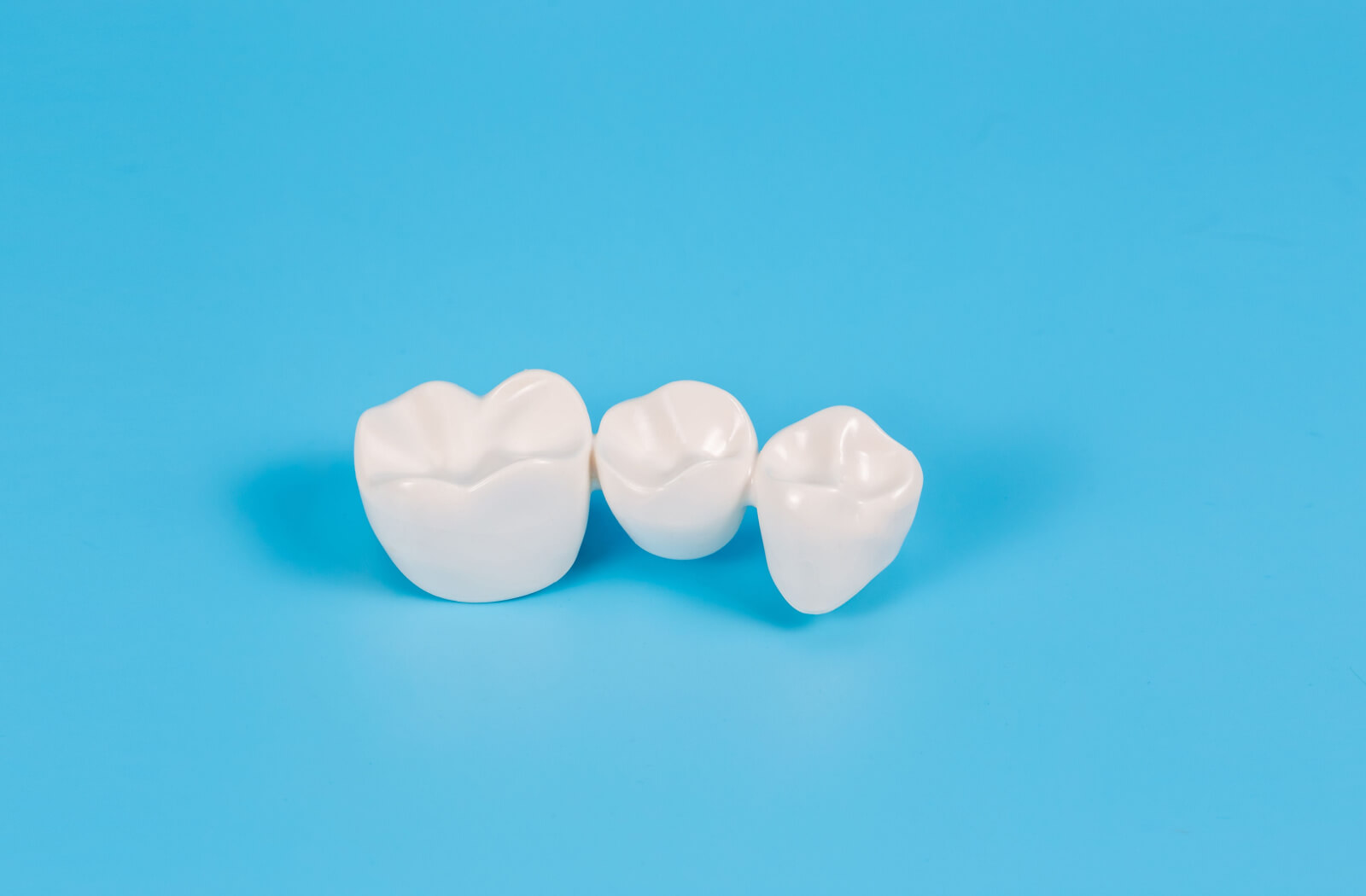 A set of dental crowns against a blue background.